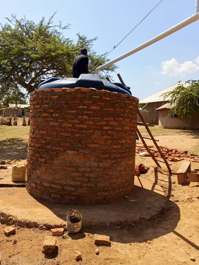 A water tank surrounded by a circular brick wall with a white pipe above it