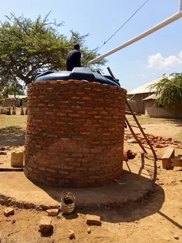 A water tank surrounded by a circular brick wall with a white pipe above it